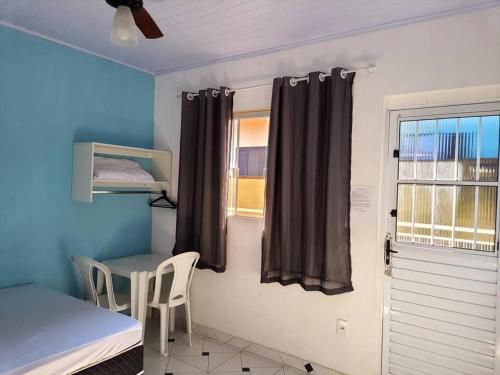 a room with a bed and a table and a window at Suites do Rafa Ubatuba in Ubatuba