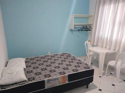 a bedroom with a bed and a table and chairs at Suites do Rafa Ubatuba in Ubatuba