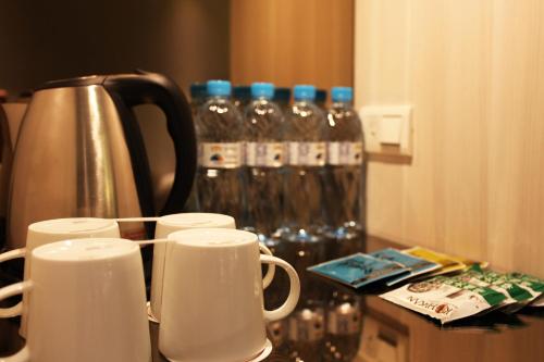 un groupe de tasses sur un comptoir avec bouteilles d'eau dans l'établissement Sankaikan Hotel, à Puzi