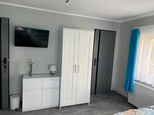 a bedroom with a white cabinet and a tv on the wall at Gaspard in Sarbinowo