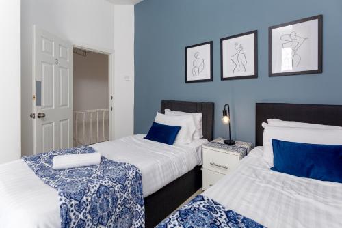 2 Betten in einem Zimmer mit blauen Wänden in der Unterkunft Air Host and Stay - Spacious 5-Bed Retreat in Edge Grove Sleeps 9 in Liverpool