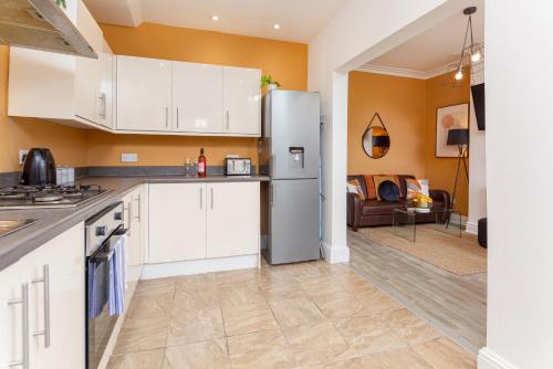 a kitchen with a refrigerator and a living room at Air Host and Stay - Spacious 5-Bed Retreat in Edge Grove Sleeps 9 in Liverpool