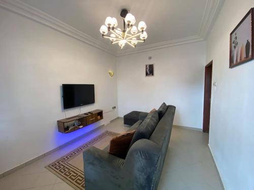 a living room with a couch and a flat screen tv at SereneLux Home in Cotonou