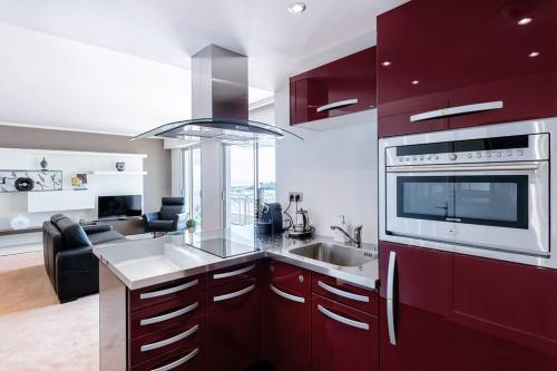 une cuisine avec armoires rouges et appareils en acier inoxydable dans l'établissement Appt spacieux FACE MER - 2 chambres - 6 personnes, à Pornichet