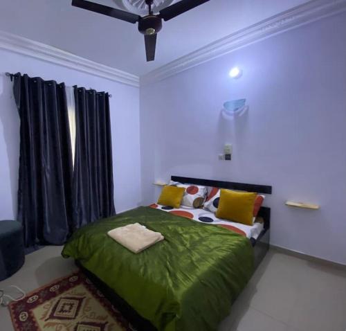 Un dormitorio con una cama verde y una ventana en SereneLux Home, en Cotonou