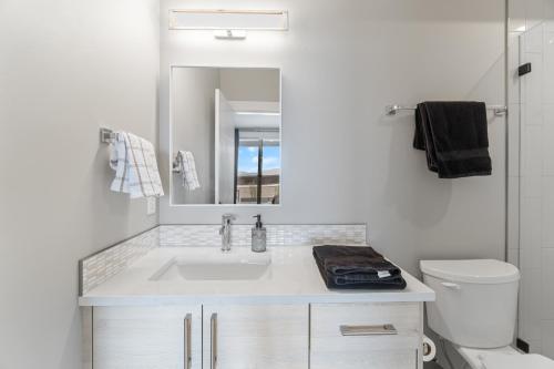 a white bathroom with a sink and a mirror at Luxury Home with Amazing Lake Okanagan Views in Kelowna