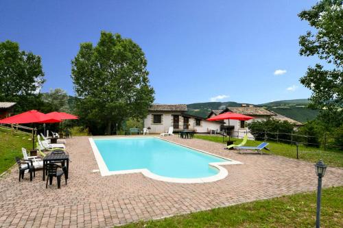 ein Pool mit Tischen und Stühlen und ein Haus in der Unterkunft Agriturismo Valle Tezze in Cascia