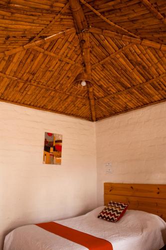 a bed in a room with a wooden ceiling at La Estancia Chincha Hotel in Chincha Alta