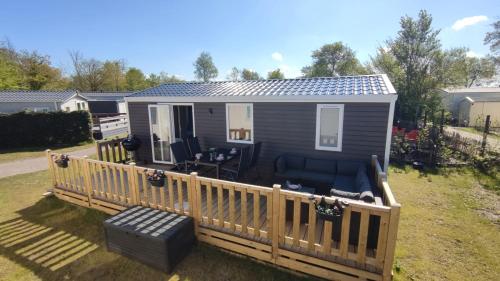 a mobile home with a wooden deck with a porch at MOBILHEIM HERZ LAUWERSOOG - Chalet Pampusplaat in Lauwersoog