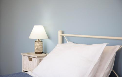a bed with a white pillow and a lamp on a night stand at The Garden House in Aegina Town