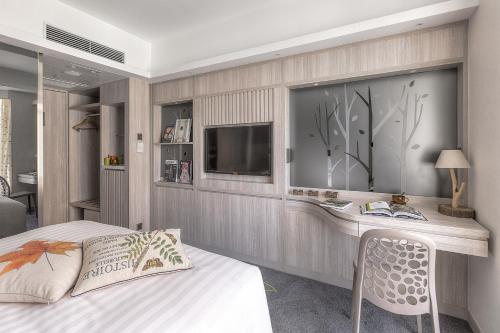 a bedroom with a bed and a tv on a wall at Stanford Hillview Hotel Hong Kong in Hong Kong