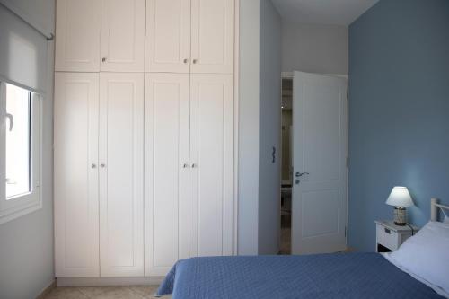 a bedroom with white cabinets and a blue bed at The Garden House in Aegina Town