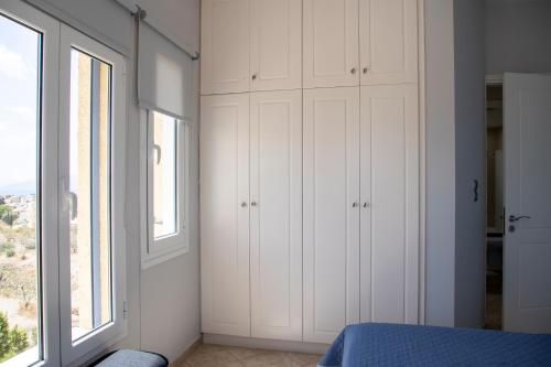 a bedroom with white cabinets and a window at The Garden House in Aegina Town
