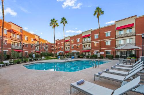 a pool with lounge chairs and a building with palm trees at Hyatt Place Phoenix Chandler - Fashion Center in Chandler