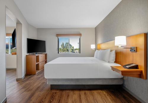 - une chambre avec un grand lit et une télévision dans l'établissement Hyatt Place Phoenix Chandler - Fashion Center, à Chandler