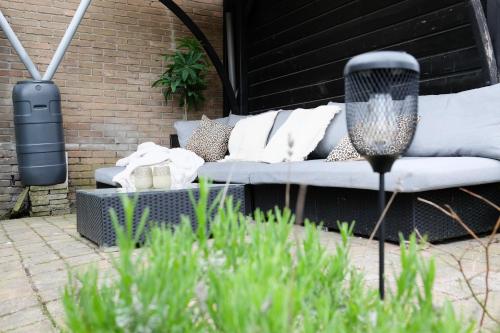 a white couch sitting on a patio next to a brick wall at Beach Lodge 24 - Noordwijk aan Zee - met eigen tuin in Noordwijk