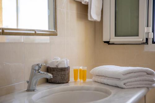 a bathroom sink with towels and a glass of orange juice at The Garden House in Aegina Town