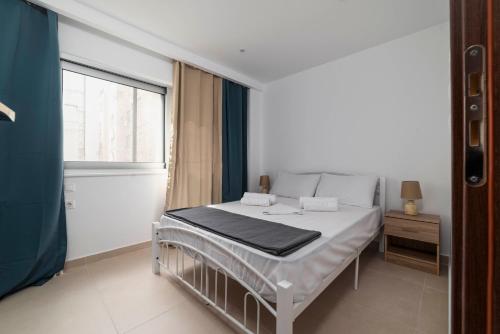 białe łóżko w pokoju z oknem w obiekcie Sweet and Comfy 2BD apartment next to metro and Archeological Museum w Atenach