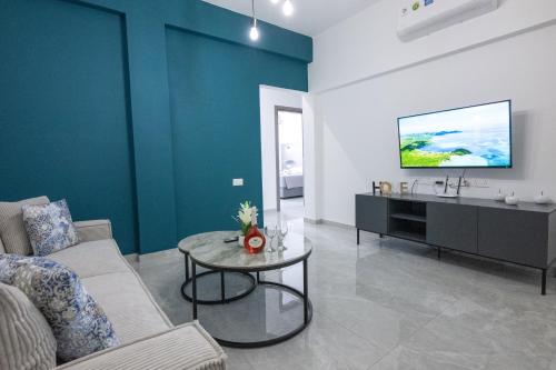 a living room with a couch and a tv on a wall at Bellagio Napa Suites in Ayia Napa