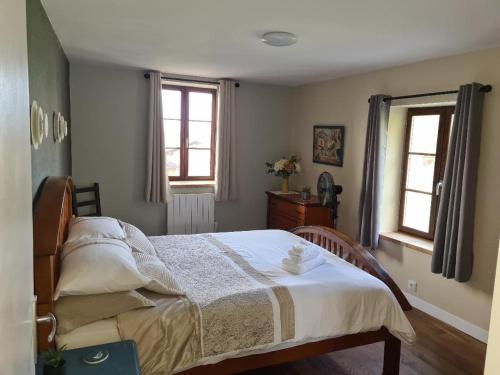 a bedroom with a bed and two windows at La Maison du Lac Lavaud in Saint-Quentin-sur-Charente