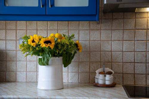 a vase filled with yellow flowers on a kitchen counter at The Garden House in Aegina Town