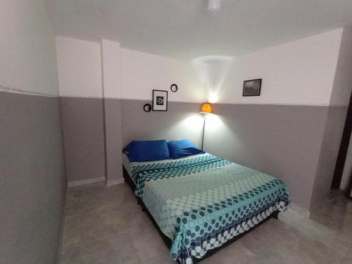 a bedroom with a bed with blue pillows and a lamp at Aparta estudio Fantástico in Bucaramanga