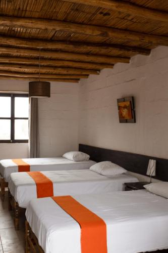 a group of four beds in a room at La Estancia Chincha Hotel in Chincha Alta