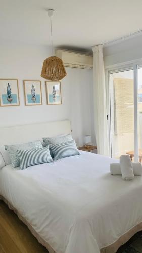 a large white bed in a bedroom with a window at Saona Coast - Apartamento reformado en playa Arenal, Jávea in Jávea