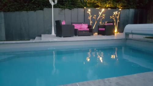 une piscine avec des chaises et un canapé dans une cour arrière la nuit dans l'établissement Residance touiker, à Bourg-en-Bresse