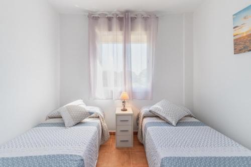 two twin beds in a room with a window at Urbanización Jardín del Golf 1 in Novo Sancti Petri
