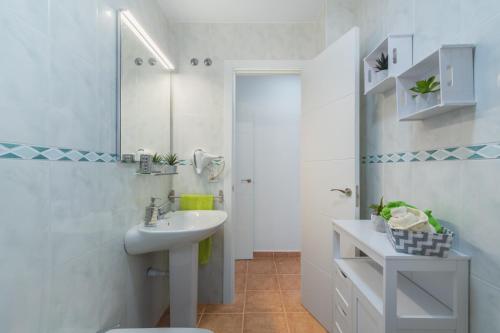 a white bathroom with a sink and a mirror at Urbanización Jardín del Golf 1 in Novo Sancti Petri