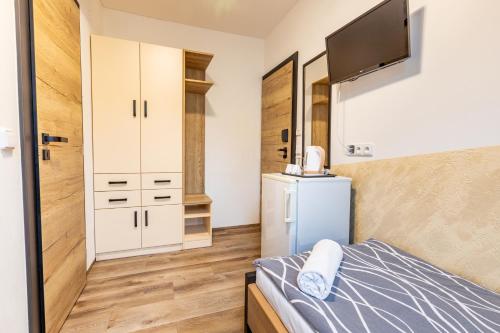 a small room with a bed and a refrigerator at Penzion Kormorán in Vranov nad Dyjí