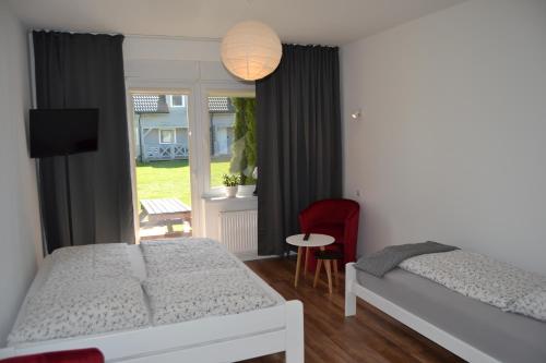 sypialnia z 2 łóżkami i czerwonym krzesłem w obiekcie Dom Goscinny Aurora w Dziwnówku