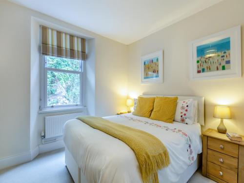 a white bedroom with a bed and a window at Poppin-uk47165 in Brixham