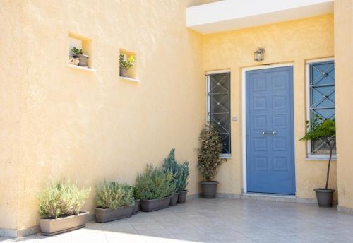 a blue door on a building with potted plants at The Garden House in Aegina Town