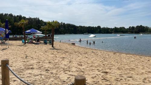 ein Strand mit einer Gruppe von Menschen, die im Wasser schwimmen in der Unterkunft Modernes Privathaus am See mit Highspeed-Internet in Sassenburg