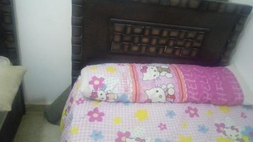 uma cama com um edredão rosa com vacas e flores em New-Fayoum Apartment em Minshāt Kamāl