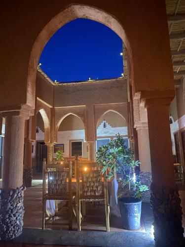 an archway with chairs and a table on a patio at night at Riad Nkob in Nkob