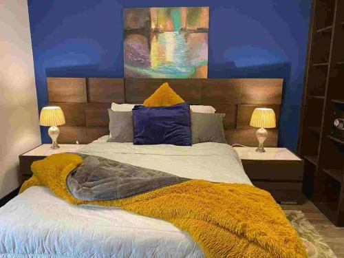 a bedroom with a bed with a yellow blanket and two lamps at Apartamento cerca a Embajada EEUU - Cayala Zona 16 