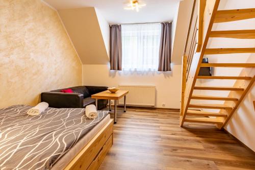 a small room with a bed and a staircase at Penzion Kormorán in Vranov nad Dyjí