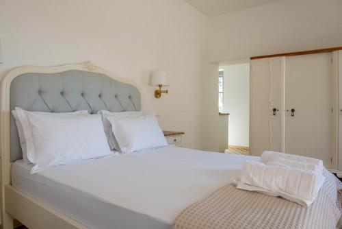 1 dormitorio con 1 cama blanca grande con almohadas blancas en Blue Coral Hydra, en Hydra