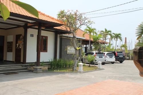 a building with cars parked in a parking lot at Prabhu Suites in Lovina