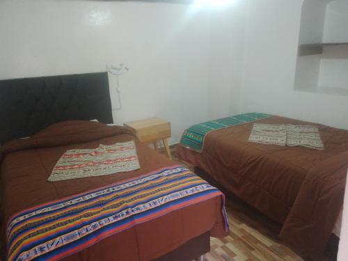 two beds sitting next to each other in a room at Hostal festival in Ollantaytambo