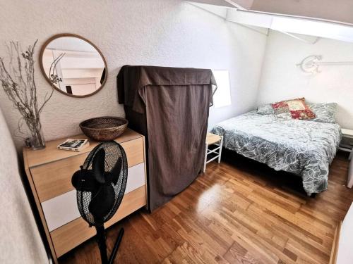 une petite chambre avec un lit et un miroir dans l'établissement Résidence Cote D'oc - Appartement deux pièces mezzanine - 4 couchages PORT LEUCATE. 2CO_35B MAE-7041, à Leucate
