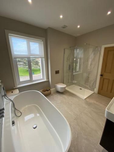 a large bathroom with a tub and a shower at Beach House in Swanage