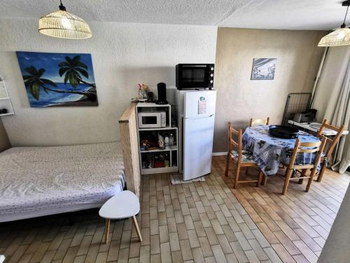 Cette chambre comprend un lit, une table et un réfrigérateur. dans l'établissement Résidence Les Arenes - STUDIO 4 PERSONNES 4 couchages PORT LEUCATE MAE-7051, à Leucate