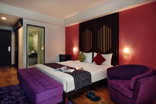 a bedroom with a large bed and a purple chair at Mercure Pontianak City Center in Pontianak