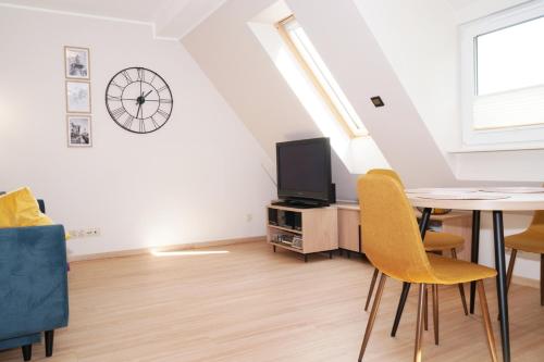 uma sala de estar com uma mesa e um relógio na parede em Przytulne Poddasze w Gdańsku em Gdansk