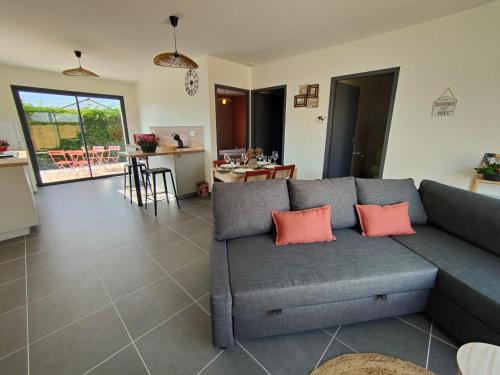 - un salon avec un canapé gris et deux oreillers orange dans l'établissement Les bambous - 2 logements 10min du zoo neuf-confort-famille-jeux pour enfants, à Saint-Romain-sur-Cher