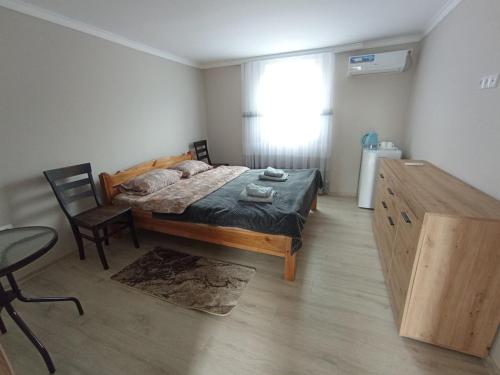 a bedroom with a bed and a table and a window at Family House in Makarovka